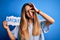 Young beautiful blonde woman with blue eyes holding banner with brexit message with happy face smiling doing ok sign with hand on Royalty Free Stock Photo