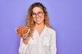 Young beautiful blonde woman with blue eyes holding bowl with healthy almond snack with a happy face standing and smiling with a Royalty Free Stock Photo