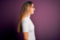 Young beautiful blonde woman with blue eyes wearing casual t-shirt over purple background looking to side, relax profile pose with Royalty Free Stock Photo