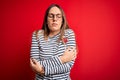 Young beautiful blonde woman with blue eyes wearing glasses standing over red background shaking and freezing for winter cold with Royalty Free Stock Photo