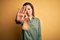 Young beautiful blonde woman with blue eyes wearing green shirt over yellow background doing stop sing with palm of the hand Royalty Free Stock Photo