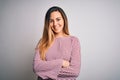 Young beautiful blonde woman with blue eyes wearing stiped t-shirt over white background happy face smiling with crossed arms Royalty Free Stock Photo