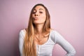 Young beautiful blonde woman with blue eyes wearing white t-shirt over pink background looking at the camera blowing a kiss on air Royalty Free Stock Photo