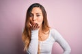 Young beautiful blonde woman with blue eyes wearing white t-shirt over pink background looking at the camera blowing a kiss with Royalty Free Stock Photo