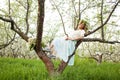 Young beautiful blonde woman in a dress in blooming apple garden - outdoors