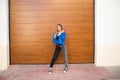 young and beautiful blonde woman dressed in black t-shirt and blue leather jacket and jeans on wooden background poses for photos Royalty Free Stock Photo