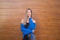 young and beautiful blonde woman dressed in black t-shirt and blue leather jacket and jeans on wooden background poses for photos Royalty Free Stock Photo