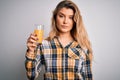 Young beautiful blonde woman drinking glass of healthy orange juice over white background with a confident expression on smart Royalty Free Stock Photo