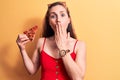 Young beautiful blonde woman eating an slice of pizza wearing summer dress covering mouth with hand, shocked and afraid for Royalty Free Stock Photo