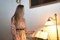 Young, beautiful, blonde woman in flower dress, leafing through guestbook at the reception of a luxurious hotel. Concept travel, Royalty Free Stock Photo