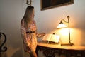 Young, beautiful, blonde woman in flower dress, leafing through guestbook at the reception of a luxurious hotel. Concept travel, Royalty Free Stock Photo