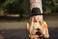 Young, beautiful, blonde woman with green eyes and hat, holding a dry leaf in her hands with melancholic look. Concept looks,