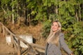 Young, beautiful, blonde woman with green eyes leaning on a wooden railing, relaxed looking at the camera very smiling and happy. Royalty Free Stock Photo