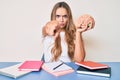 Young beautiful blonde woman holding brain while studying for school pointing with finger to the camera and to you, confident