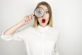 Young beautiful blonde woman holding magnifying glass near her eye looks surprised isolated white background Royalty Free Stock Photo