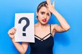 Young beautiful blonde woman holding question mark stressed and frustrated with hand on head, surprised and angry face Royalty Free Stock Photo