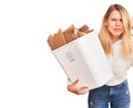 Young beautiful blonde woman holding recycle paper bin annoyed and frustrated shouting with anger, yelling crazy with anger and Royalty Free Stock Photo