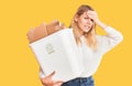 Young beautiful blonde woman holding recycle paper bin stressed and frustrated with hand on head, surprised and angry face Royalty Free Stock Photo