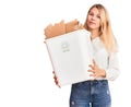 Young beautiful blonde woman holding recycle paper bin thinking attitude and sober expression looking self confident Royalty Free Stock Photo