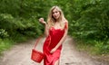 Young, beautiful blonde woman with long hair in a red dress posing with an apple in one hand and a basket in the other hand