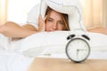 Young beautiful blonde woman lying in bed suffering from alarm c Royalty Free Stock Photo