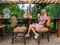 Young beautiful blonde woman in a pink dress sits with a cup of coffee in her hands in a cafe or restaurant in vintage style in Royalty Free Stock Photo