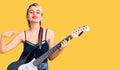 Young beautiful blonde woman playing electric guitar pointing finger to one self smiling happy and proud Royalty Free Stock Photo