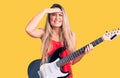 Young beautiful blonde woman playing electric guitar stressed and frustrated with hand on head, surprised and angry face Royalty Free Stock Photo