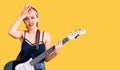 Young beautiful blonde woman playing electric guitar stressed and frustrated with hand on head, surprised and angry face Royalty Free Stock Photo