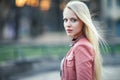 Young beautiful blonde woman portrait posing in city street on s