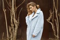 Young beautiful blonde woman posing in blue coat outdoors Royalty Free Stock Photo