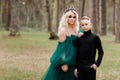 Young beautiful blonde woman queen with young boy in black outfit. Princess mother walks with son. autumn green forest mystic. Royalty Free Stock Photo