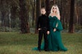 Young beautiful blonde woman queen with young boy in black outfit. Princess mother walks with son. autumn green forest mystic. Royalty Free Stock Photo