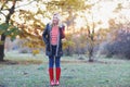 Young beautiful blonde woman in red rubber boots posing in autumn park Royalty Free Stock Photo