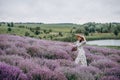 Young beautiful blonde woman in a romantic dress, a straw hat and a basket of flowers dancing in a lavender field. Soft selective Royalty Free Stock Photo