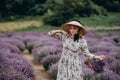 Young beautiful blonde woman in a romantic dress, a straw hat and a basket of flowers dancing in a lavender field. Soft selective Royalty Free Stock Photo