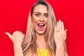 Young beautiful blonde woman showing engagement ring over isolated red background pointing thumb up to the side smiling happy with Royalty Free Stock Photo