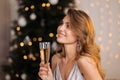 A young beautiful blonde woman in a silver cocktail dress holds a glass of champagne. Smiling and posing against the Royalty Free Stock Photo