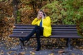 Young, beautiful, blonde woman sits on a bench in the park and talking on the phone Royalty Free Stock Photo