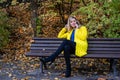 Young, beautiful, blonde woman sits on a bench in the park and talking on the phone Royalty Free Stock Photo