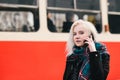 Young beautiful blonde woman talking on the phone on a background of red train station. Outdoor portrait of a girl. Royalty Free Stock Photo