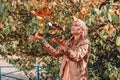 Young beautiful blonde woman throwing up fallen autumn leaves over her head standing on the ground in the park Royalty Free Stock Photo