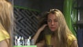 Young beautiful blonde woman turns on hair dryer and dries long hair
