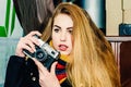 Young beautiful blonde woman with a vintage camera takes pictures in a cafe. Winter portraits of the photographer Royalty Free Stock Photo