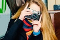 Young beautiful blonde woman with a vintage camera takes pictures in a cafe. Winter portraits of the photographer Royalty Free Stock Photo