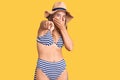Young beautiful blonde woman wearing bikini and hat laughing at you, pointing finger to the camera with hand over mouth, shame Royalty Free Stock Photo