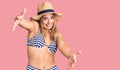 Young beautiful blonde woman wearing bikini and hat looking at the camera smiling with open arms for hug Royalty Free Stock Photo