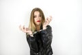 Young beautiful blonde woman wearing black leather jacket looks desparate being handcuffed on isolated white background