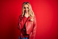 Young beautiful blonde woman wearing casual jacket standing over isolated red background looking confident at the camera smiling Royalty Free Stock Photo