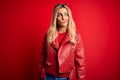 Young beautiful blonde woman wearing casual jacket standing over isolated red background smiling looking to the side and staring Royalty Free Stock Photo